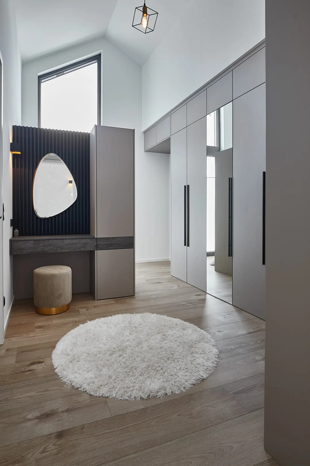 Ankleidezimmer mit greige Schrankfronten, Spiegeltüren und Schminkplatz vor schwarzer Lamellenwand
