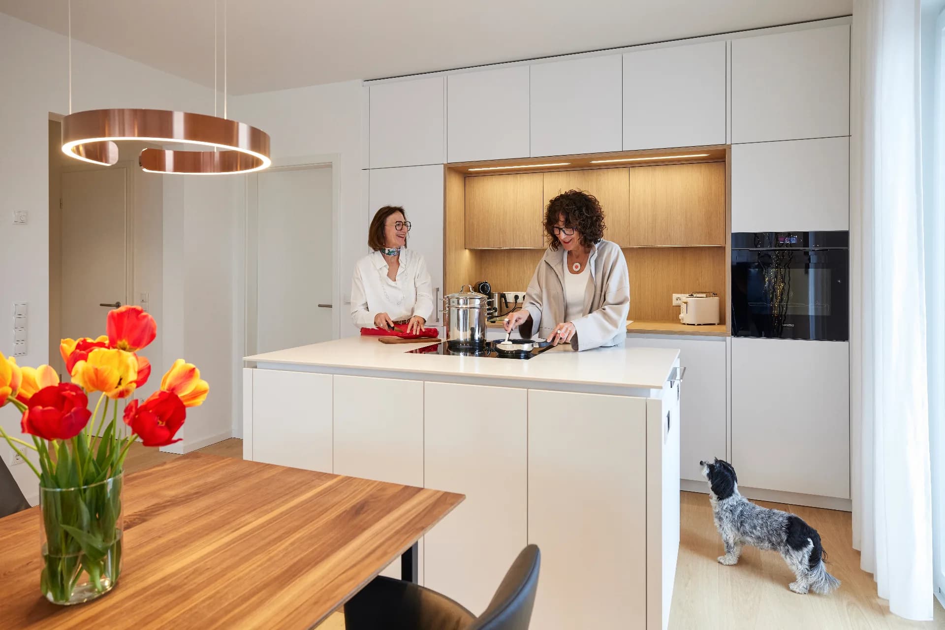 Zwei Frauen kochen gemeinsam in ihrer neu eingebauten weißen Küche mit Eichennische
